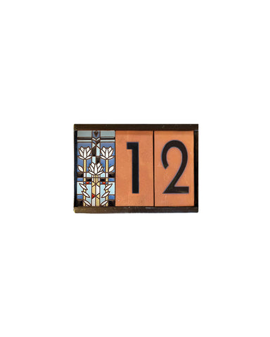 Decorative house number sign with colorful design and numbers on a white background